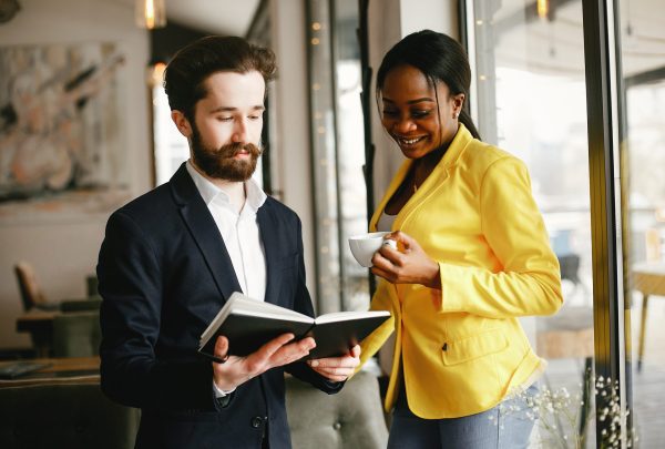 Handsome man in a black suit. Woman in a yellow jacket. Businessman working in a office
